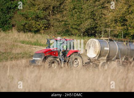 Ein großer Red Case 340 Magnum Traktor schleckt einen 30 Tonnen schweren Wasseranhänger über Ackerland Stockfoto