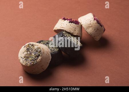 Solide natürliche Shampoo-Bars mit Blütenblättern, Zero Waste Konzept auf braunem Hintergrund Stockfoto