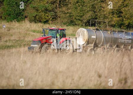 Ein großer Red Case 340 Magnum Traktor schleckt einen 30 Tonnen schweren Wasseranhänger über Ackerland Stockfoto