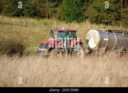 Ein großer Red Case 340 Magnum Traktor schleckt einen 30 Tonnen schweren Wasseranhänger über Ackerland Stockfoto