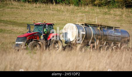 Ein großer Red Case 340 Magnum Traktor schleckt einen 30 Tonnen schweren Wasseranhänger über Ackerland Stockfoto