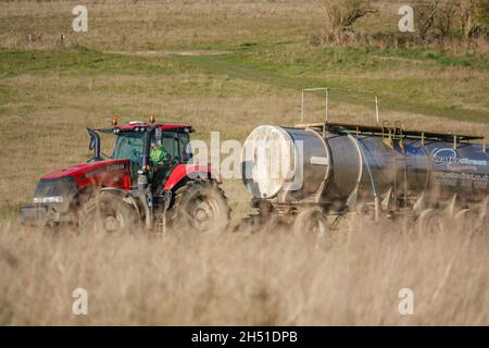 Ein großer Red Case 340 Magnum Traktor schleckt einen 30 Tonnen schweren Wasseranhänger über Ackerland Stockfoto