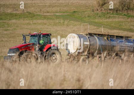 Ein großer Red Case 340 Magnum Traktor schleckt einen 30 Tonnen schweren Wasseranhänger über Ackerland Stockfoto