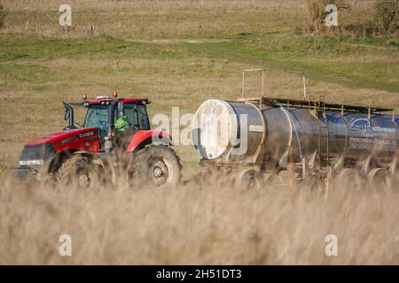 Ein großer Red Case 340 Magnum Traktor schleckt einen 30 Tonnen schweren Wasseranhänger über Ackerland Stockfoto