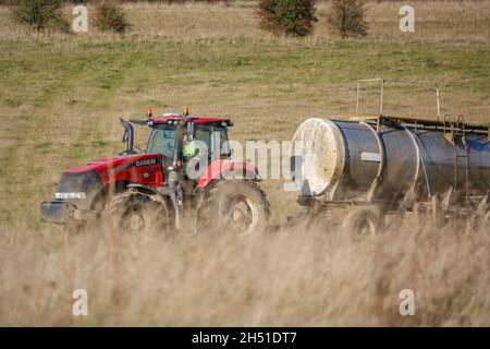 Ein großer Red Case 340 Magnum Traktor schleckt einen 30 Tonnen schweren Wasseranhänger über Ackerland Stockfoto