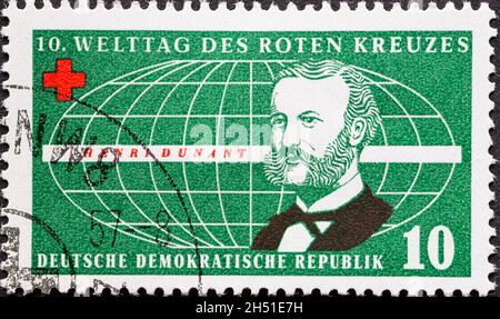 DEUTSCHLAND, DDR - UM 1957 : eine Briefmarke aus Deutschland, DDR mit einem Porträt von Henry Dunant, Mitbegründer des Roten Kreuzes, vor einem stilisierten Stockfoto