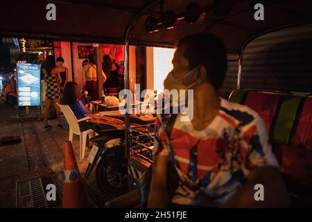 Bangkok, Thailand. November 2021. Barmädchen und ein Tuk-Tuk-Fahrer werden im Nachtleben-Viertel auf der Sukhumvit-Straße auf ihre Gäste warten sehen.Nachdem Thailand das Land am 1. November für vollständig geimpfte Reisende wiedereröffnet hat, Eine Kampagne wurde in der Nana-Nightlife-Zone gestartet, einem der gut erkennbaren Nightlife-Viertel in Bangkok, scheint aufgrund der Regierungspolitik, die den Verkauf von Alkohol in Bars nur von 17:00 bis 21:00 Uhr zulässt, immer noch etwas zu lockern. Kredit: SOPA Images Limited/Alamy Live Nachrichten Stockfoto