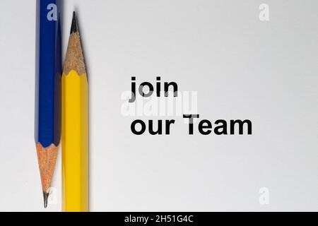 Zwei geschärfte Stifte zeigen in entgegengesetzte Richtungen und werden vertikal auf weißem Hintergrund platziert. Der Solgan join our Team ist schwarz auf Th geschrieben Stockfoto