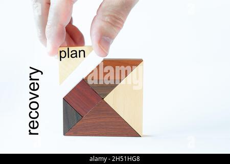 Ein fehlender Stein wird von einer Hand in ein edles Holztagramm eingefügt. Der Textplan wird auf einen Block und auf den Hintergrund geschrieben und die Textwiederherstellung ist Stockfoto