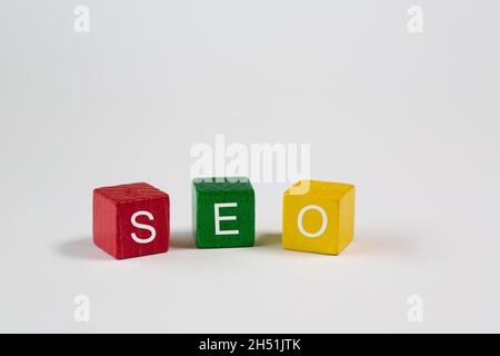 Die Abkürzung SEO - Search Engine Optimization - wird vor einem weißen Hintergrund auf einem roten, grünen und gelben Block mit jeweils einem Buchstaben notiert und ist i Stockfoto