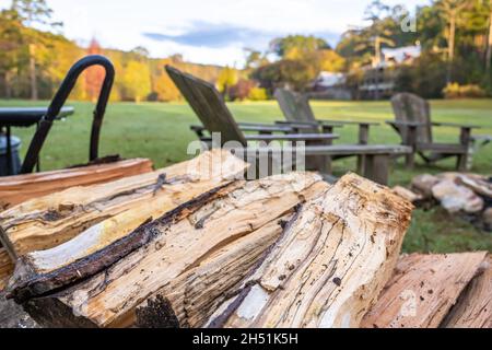 Feuerholz in der Nähe einer Feuerstelle mit einem Kreis von Adirondack-Stühlen im wunderschönen und historischen Glen-Ella Springs Inn & Restaurant in Clarkesville, Georgia. Stockfoto