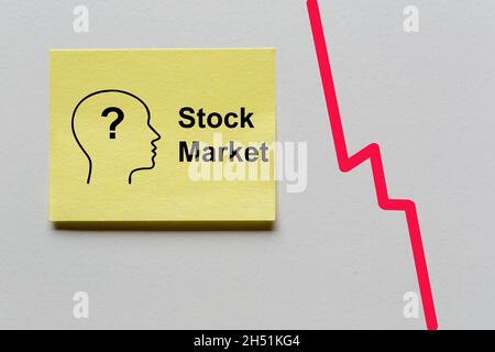 Gelber Notizaufkleber mit Silhouette eines Kopfes mit Fragezeichen und dem Text: Stock Market. Rechts zeigt eine rote Kurve steil nach unten Stockfoto