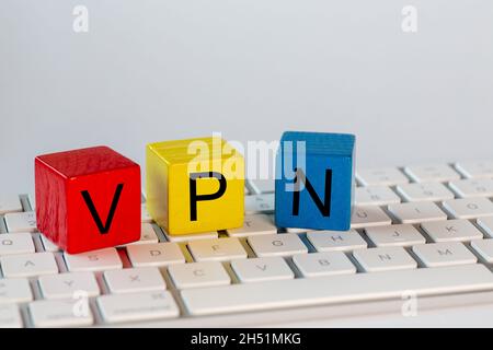 Bunte Blöcke mit den Buchstaben VPN, die für Virtual Private Network stehen. Die Blöcke befinden sich auf einer hellen Computertastatur und sind mit weißem Bac isoliert Stockfoto