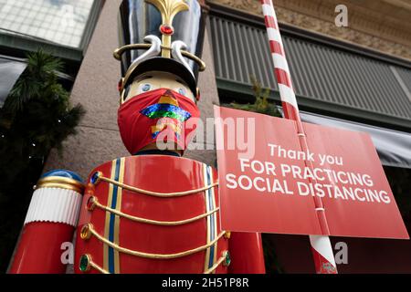 Weihnachten, Weihnachtseinkäufe während des COVID Tragen von Masken und soziale Distanzierungsanforderungen, Schild vor dem Einkaufszentrum Stockfoto
