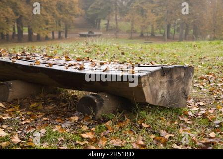Bank mit Blättern in einem Park im Herbst bedeckt Stockfoto