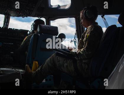 LT. Col. Jamila Fitzpatrick, Flugkommandant der 6th Airlift Squadron, ruft während des vierteljährlichen Trainings der 535. Airlift Squadron auf den Hawaii-Inseln am 3. November 2021 Injektion aus einem Spielbuch hervor. Air Mobility Command und Pacific Air Forces Airmen flogen über die hawaiianischen Inseln, um an mehreren Trainingsszenarien während des Fluges zu teilnehmen. (USA Luftwaffe Foto von Senior Airman Alan Ricker) Stockfoto