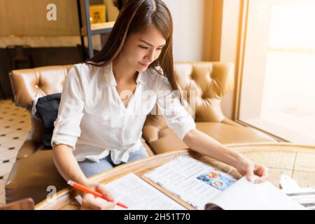 Junge Frau beim Lesen der Speisekarte im Restaurant. Stockfoto