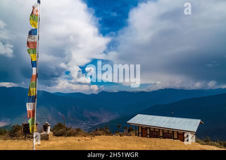 Traditionelles Gebet Tibetisch-buddhistische Flaggen Lung Ta und kleines Haushaltsgebäude des Phajoding-Klosters hoch im Himalaya-Gebirge in Bhutan. Vi Stockfoto