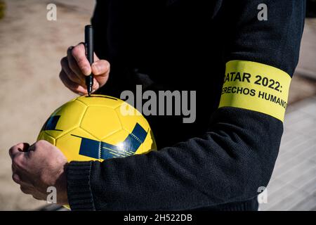 Madrid, Spanien. November 2021. Ein Protestler schreibt während des Protestes vor dem spanischen Fußballverband in Madrid über einen Fußball. Internationale Aktivisten von Amnesty veranstalteten einen Protest vor dem spanischen Fußballverband, in dem sie forderten, dass sich der Verband beim Bau von Qatar-Stadien für die FIFA-Weltmeisterschaft 2022 gegen Menschenrechtsverletzungen aussprecht. Kredit: SOPA Images Limited/Alamy Live Nachrichten Stockfoto