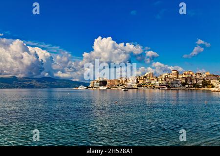 Panoramablick auf Saranda Bucht und Stadt und Stadthafen entlang der Küste, Albanien. Sonniger Sommertag. Wunderschöne Wolken am Himmel. Korfu Insel sichtbar auf Stockfoto