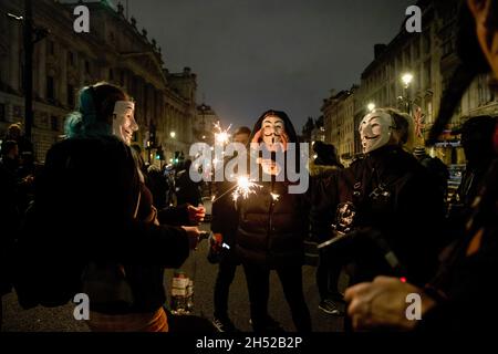 London, Großbritannien. November 2021. Demonstranten, die Guy Fawkes-Masken tragen, leuchten während des Protestes Lichtfunkler auf.Demonstranten versammelten sich am Trafalgar-Platz zum jährlichen Millionen-Maske-Marsch. Die jährliche Demonstration wurde zum ersten Mal von der haktivistischen Gruppe Anonymous am Guys Fawkes Day im Jahr 2012 aufgerufen. Kredit: SOPA Images Limited/Alamy Live Nachrichten Stockfoto