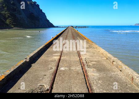 Der historische Betonwharf an der Tokomaru Bay, Neuseeland (erbaut 1940), der sich bis weit in den Ozean erstreckt Stockfoto