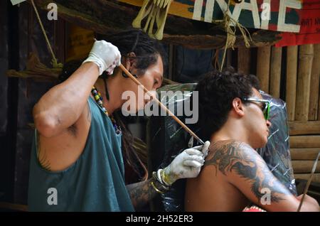 Thai Mann Tattoo Künstler Menschen schreiben Zeichnung Tattoo auf Rückseite von ausländischen Reisenden Männer Reise besuchen Rest entspannen Sie sich in lokalen Tattoo-Shop in Ao Nang Railay Bay Stockfoto