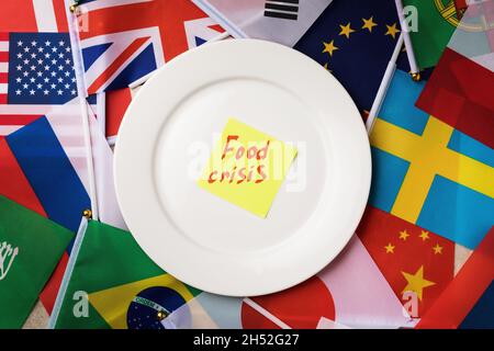Aufkleber mit Text in einem weißen Schild auf dem Hintergrund der Flaggen verschiedener Länder, das Konzept der Nahrungsmittelkrise in der Welt Stockfoto