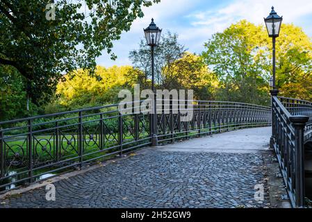 An einem schönen sonnigen Tag überquert eine eiserne Fußgängerbrücke den Fluss. Stockfoto