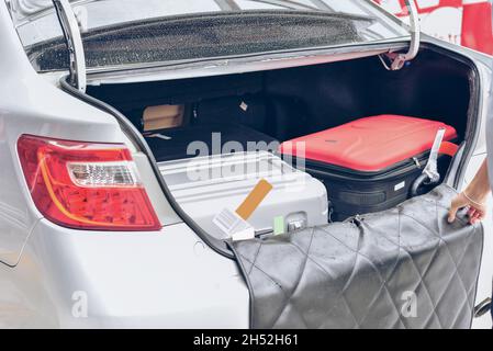 Chauffeur, der Koffer in den Kofferraum des Autos legt. Personen, die ein Taxi von einem Flughafen nehmen und eine Handgepäcktasche zum Auto laden. Gepäck für das Reisekonzept. Stockfoto