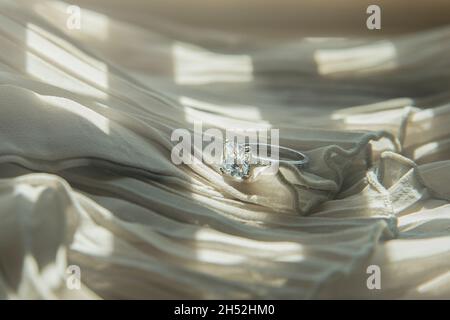 Nahaufnahme des eleganten Diamantrings auf grauem Schal-Hintergrund. Luxus Diamanten Schmuck Accessoire. „I Love You Darling“-Konzept. Stockfoto