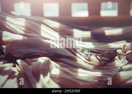 Nahaufnahme des eleganten Diamantrings auf grauem Schal-Hintergrund. Luxus Diamanten Schmuck Accessoire. „I Love You Darling“-Konzept. Stockfoto