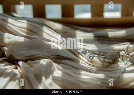 Nahaufnahme des eleganten Diamantrings auf grauem Schal-Hintergrund. Luxus Diamanten Schmuck Accessoire. „I Love You Darling“-Konzept. Stockfoto