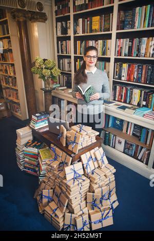 GREAT BRITAN / London / Buchhandlungen / schöne Frau, die ein Buch in einer Buchhandlung liest. Stockfoto