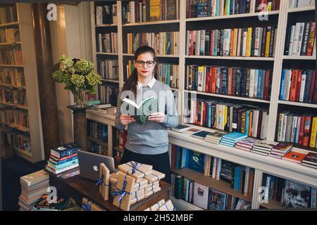 GREAT BRITAN / London / Buchhandlungen / schöne Frau, die ein Buch in einer Buchhandlung liest. Stockfoto