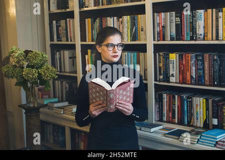 GREAT BRITAN / London / Buchhandlungen / schöne Frau, die ein Buch in einer Buchhandlung liest. Stockfoto