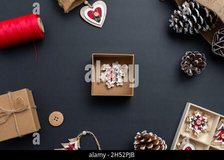 Konzept der Herstellung von Weihnachtsgeschenken mit kleinen Schachteln und Dekorationen für den Weihnachtsbaum. Box mit einer kleinen Holzdekoration bereit für die Verpackung Stockfoto