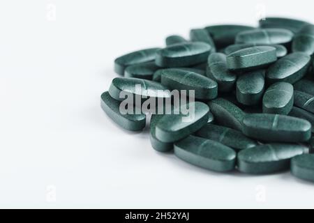 Pillen mit Vitaminen und Spirulina auf weißem Hintergrund. Sportzuschlag Stockfoto