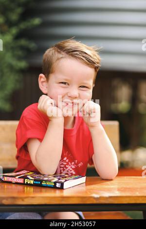Niedlicher kleiner Junge posiert für Kindergarten- oder Vorschulfotos im Außenbereich Stockfoto