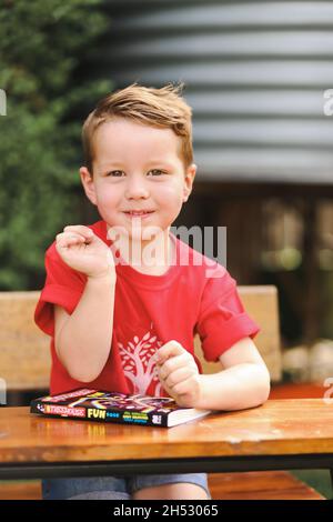 Niedlicher kleiner Junge posiert für Kindergarten- oder Vorschulfotos im Außenbereich Stockfoto
