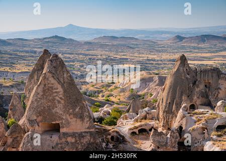 Wunderschöne Sonnenuntergangslandschaft im Tal von Cappadocia mit alten Höhlenhäusern im Vordergrund Stockfoto