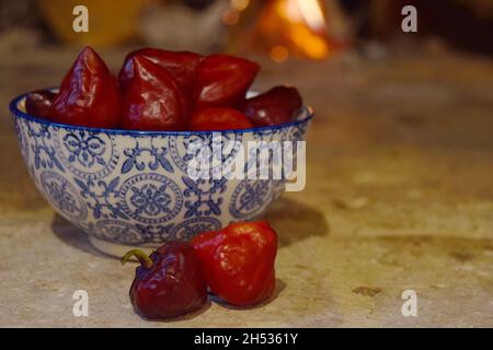 Schale mit purpurnen UFO Chilli-Paprika neben dem Holzofen Stockfoto