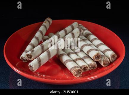 Die Sweet Sticks mit Füllung in roter Platte auf schwarzem Hintergrund. Dessert bis Tee auf schwarzem Hintergrund Stockfoto