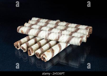 Süße Stäbchen mit Füllung auf dem Tisch mit Reflexion. Dessert für Tee auf schwarzem Hintergrund Stockfoto