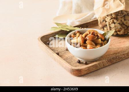 Eingelegte Honigpilze in weißer Schale und Gewürze auf beigem Hintergrund. Speicherplatz kopieren. Nahaufnahme. Stockfoto