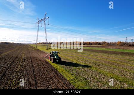 Traktor mit Pflug auf Pflug. Pflügen und Bodenbearbeitung. Landwirtschaftliche Traktor auf Anbaugebiet für die Aussaat von Samen. Traktor Während Der Feldkultivierung Stockfoto
