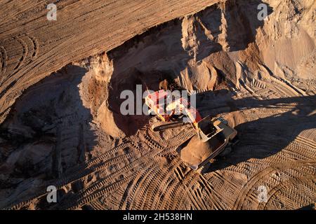 Der Bagger lädt den Sand in einen Muldenkipper im Tagebau. Entwicklung des Sandes im Tagebaus. Schwere Maschinen auf Erdarbeiten im Steinbruch. Miningtruck Stockfoto