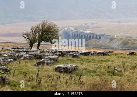 An einem nebligen Herbsttag überquert ein Personenzug das Ribblehead (Batty Moss) Viadukt, North Yorkshire, auf der Eisenbahnlinie Settle-Carlisle in Richtung Norden. Stockfoto