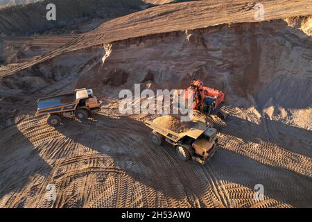 Der Bagger lädt den Sand in einen Muldenkipper im Tagebau. Entwicklung des Sandes im Tagebaus. Schwere Maschinen auf Erdarbeiten im Steinbruch. Miningtruck Stockfoto