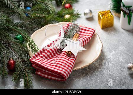 Weihnachtliche Tischeinstellung mit Teller-Feiertagskonzept auf grauem Tisch Stockfoto